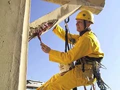 Maçon cordiste TRAPEZE en combinaison jaune au travail sur corde