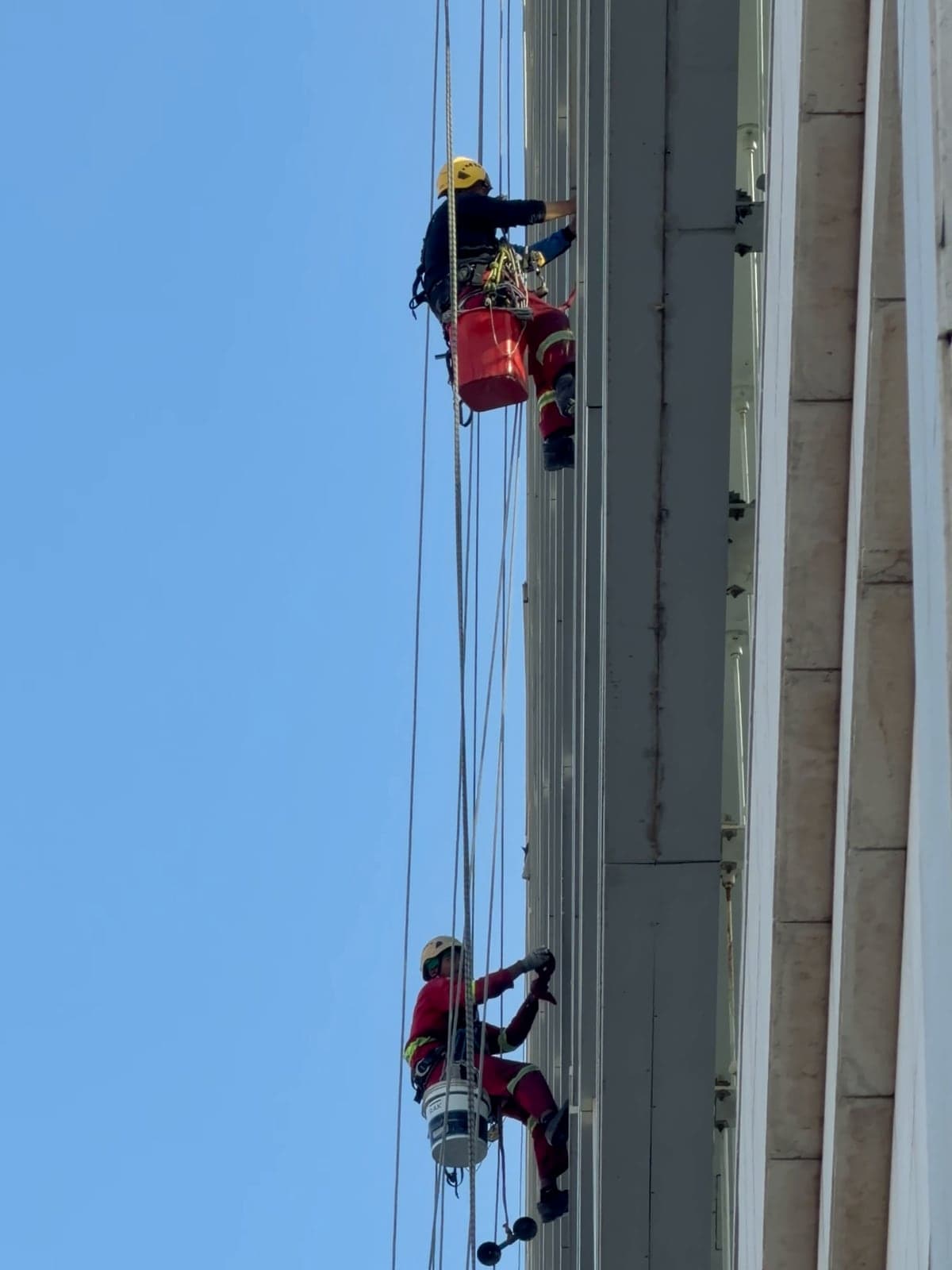 Cordiste casqué suspendu à une double corde le long d'une tour