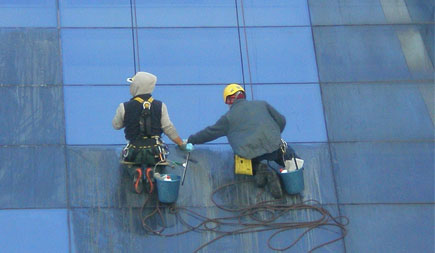 Laveurs de vitres cordistes TRAPEZE lors du nettoyage en hauteur d'un mur rideau d'un immeuble de grande hauteur